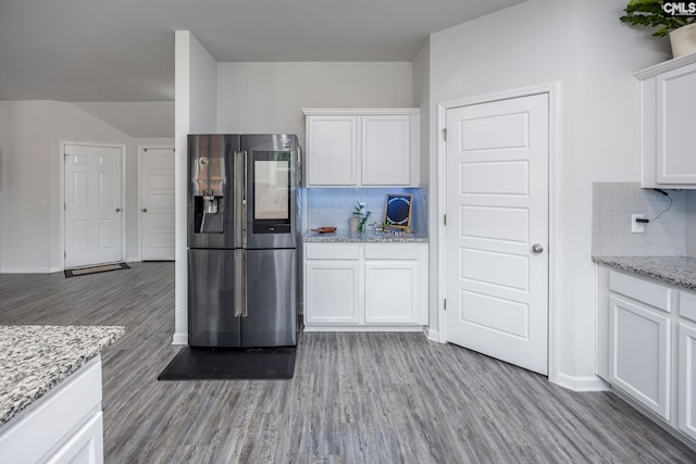 kitchen featuring light stone counters, tasteful backsplash, stainless steel fridge with ice dispenser, light hardwood / wood-style flooring, and white cabinets