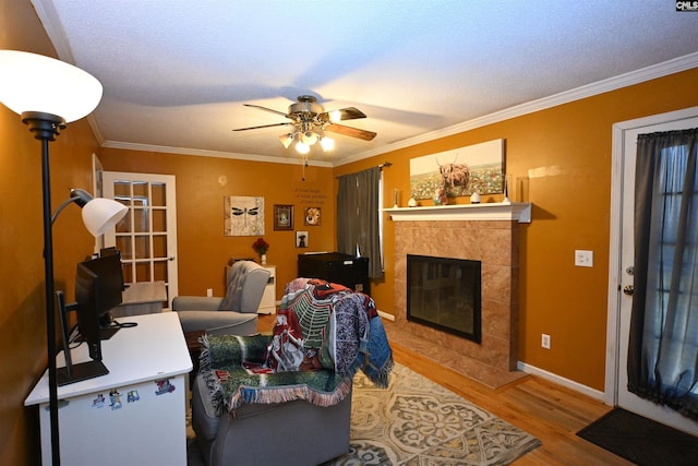 living room featuring a tiled fireplace, light hardwood / wood-style flooring, and ornamental molding