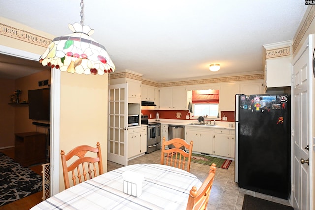 kitchen with cream cabinetry, sink, stainless steel appliances, and hanging light fixtures