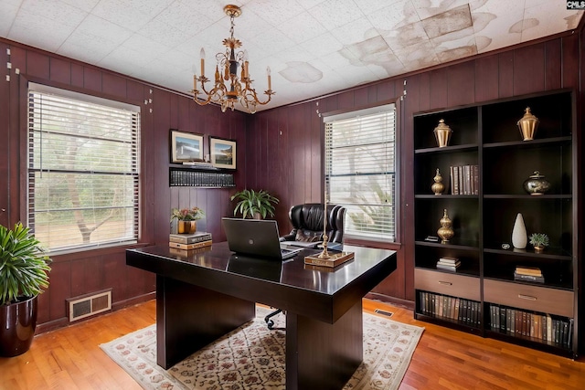 office space featuring an inviting chandelier, light hardwood / wood-style floors, and wood walls