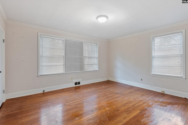 spare room featuring crown molding, wood-type flooring, and a wealth of natural light