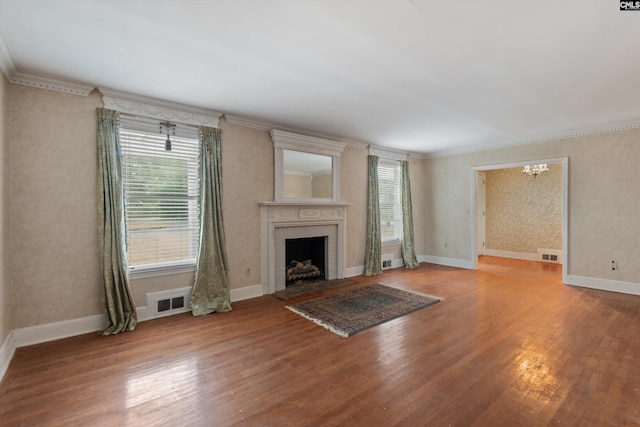 unfurnished living room with hardwood / wood-style floors, a fireplace, ornamental molding, and a chandelier