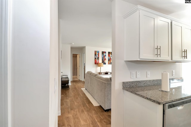 kitchen with white cabinetry, light hardwood / wood-style floors, stainless steel dishwasher, and dark stone counters