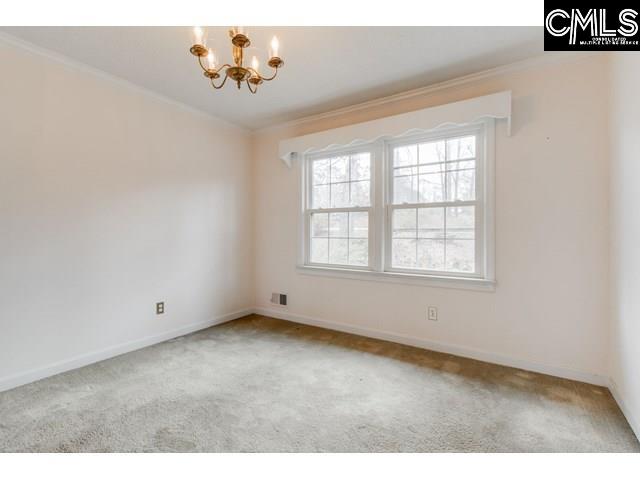 carpeted spare room featuring crown molding and a notable chandelier