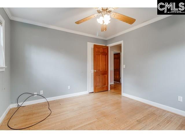 empty room featuring ornamental molding, ceiling fan, and light wood-type flooring