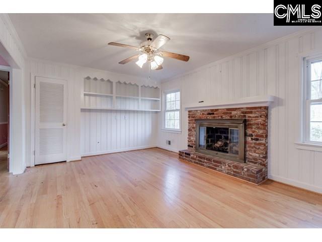 unfurnished living room featuring plenty of natural light, hardwood / wood-style floors, and a brick fireplace