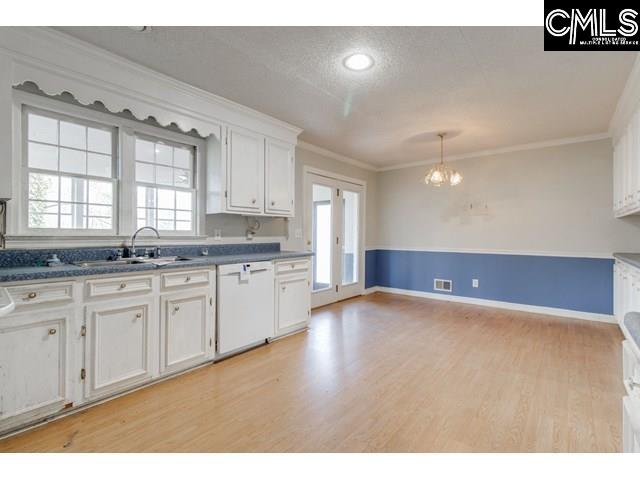 kitchen featuring white cabinetry, dishwasher, pendant lighting, and ornamental molding