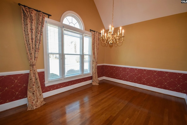 spare room with vaulted ceiling, wood-type flooring, and a notable chandelier