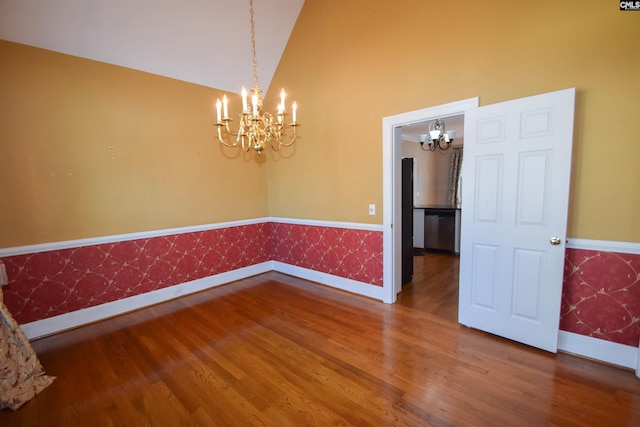 empty room with high vaulted ceiling, hardwood / wood-style floors, and a notable chandelier