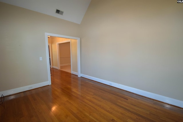 unfurnished room with wood-type flooring and high vaulted ceiling