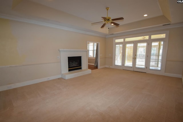 unfurnished living room featuring crown molding, a tray ceiling, and light carpet