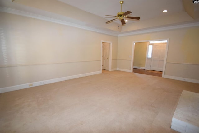 empty room featuring light carpet, a tray ceiling, crown molding, and ceiling fan