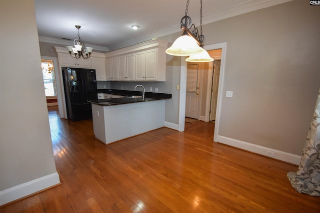 kitchen featuring decorative light fixtures, sink, white cabinets, and black refrigerator with ice dispenser