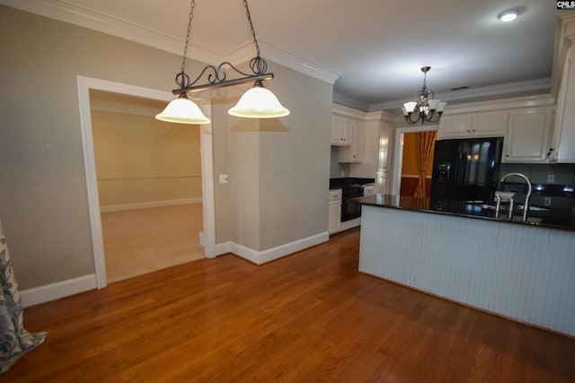 kitchen with sink, decorative light fixtures, white cabinets, and black fridge