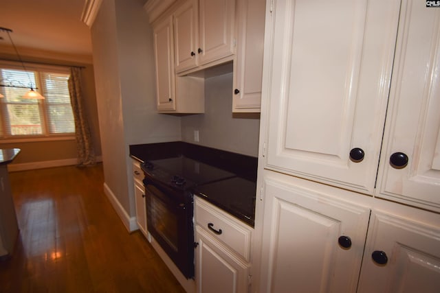 kitchen with electric stove, dark wood-type flooring, hanging light fixtures, and white cabinets