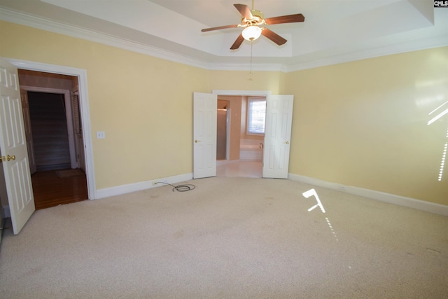 carpeted spare room with ornamental molding, a raised ceiling, and ceiling fan