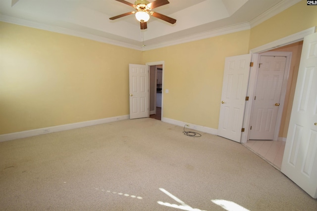 unfurnished bedroom with crown molding, light colored carpet, a raised ceiling, and ceiling fan