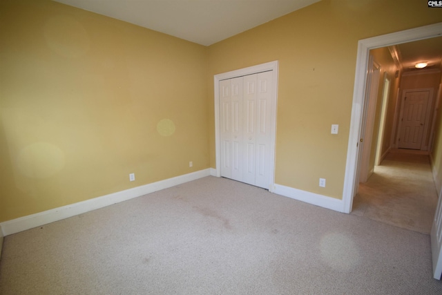 unfurnished bedroom featuring light colored carpet and a closet