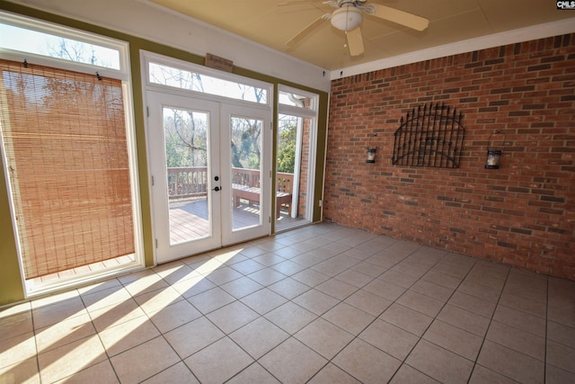 doorway to outside with light tile patterned flooring, french doors, ceiling fan, and brick wall