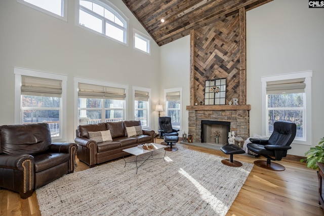 living room featuring a wealth of natural light, wood finished floors, and a stone fireplace