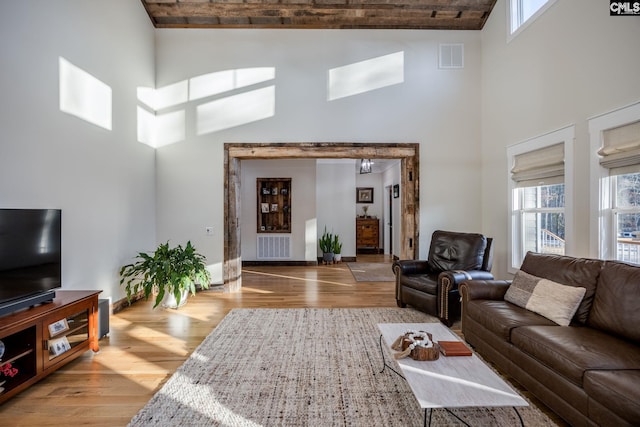 living room with a towering ceiling, wood finished floors, and visible vents