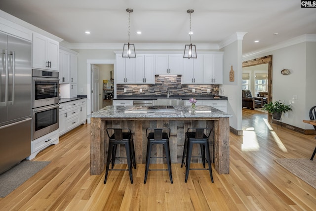 kitchen featuring stainless steel appliances, crown molding, a kitchen breakfast bar, and tasteful backsplash