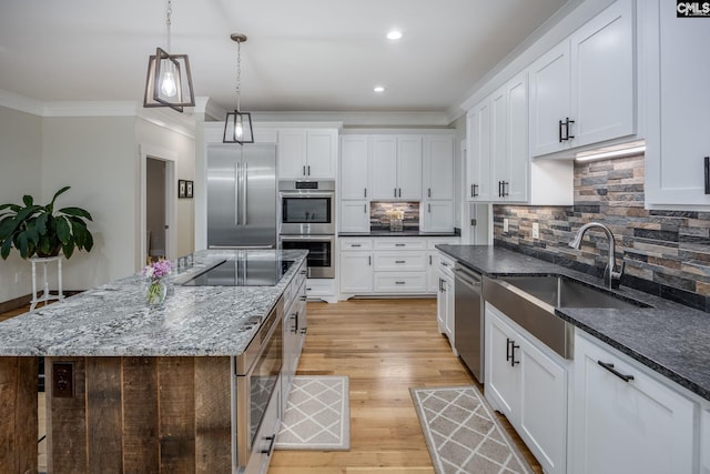 kitchen featuring a sink, white cabinets, appliances with stainless steel finishes, decorative backsplash, and crown molding