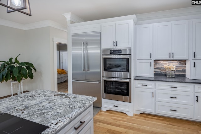 kitchen featuring stainless steel appliances, ornamental molding, and white cabinets