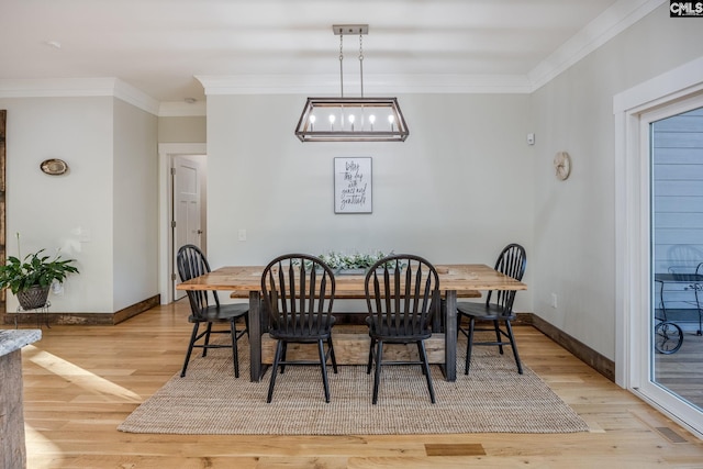 dining space featuring baseboards, light wood-type flooring, and crown molding