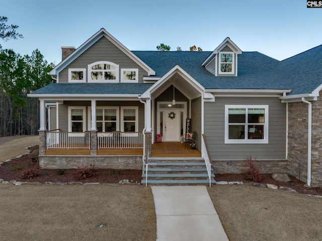 view of front facade with covered porch and roof with shingles