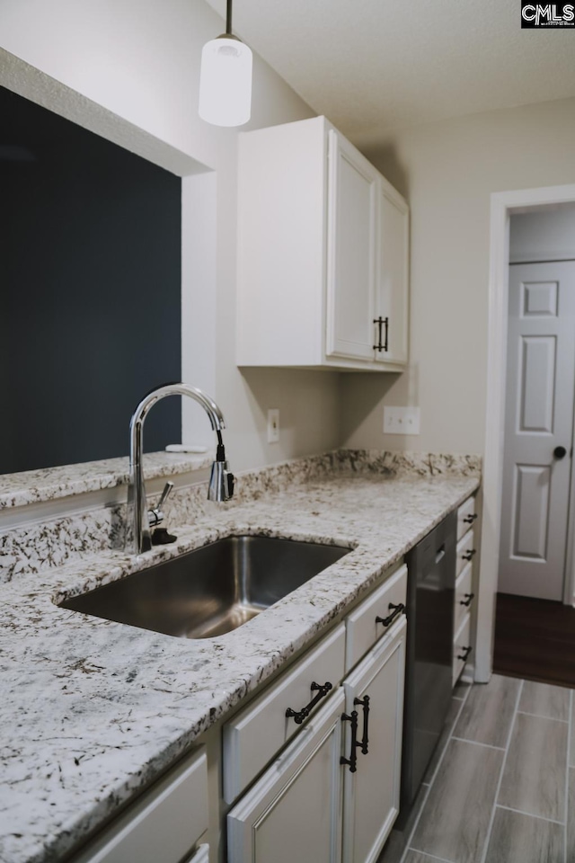 kitchen with sink, white cabinetry, decorative light fixtures, black dishwasher, and light stone countertops