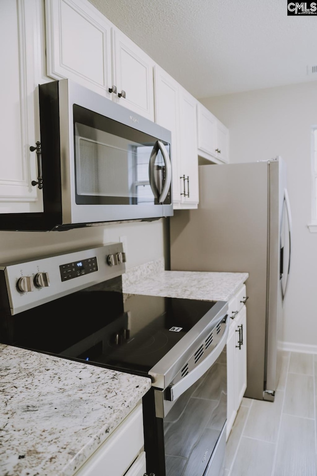 kitchen featuring light stone countertops, white cabinetry, and appliances with stainless steel finishes