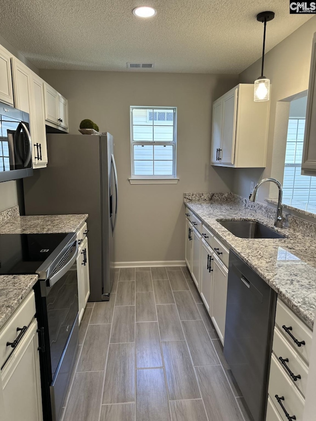 kitchen with sink, hanging light fixtures, black dishwasher, range with electric cooktop, and white cabinets