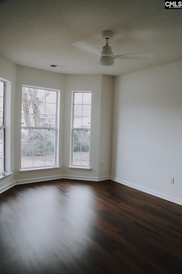 empty room with ceiling fan, dark hardwood / wood-style flooring, and a textured ceiling