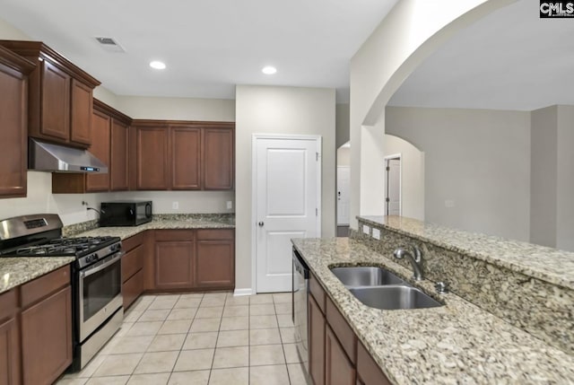 kitchen with light stone counters, sink, light tile patterned floors, and stainless steel appliances