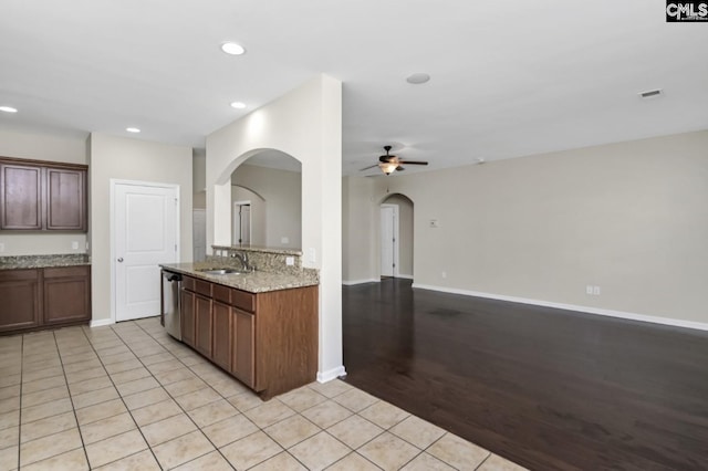 kitchen with sink, light tile patterned floors, dishwasher, ceiling fan, and light stone countertops