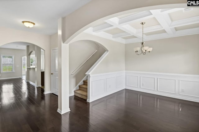 interior space featuring coffered ceiling, beam ceiling, dark wood-type flooring, and a chandelier