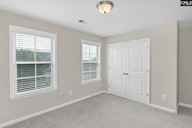 unfurnished bedroom featuring light colored carpet and a closet