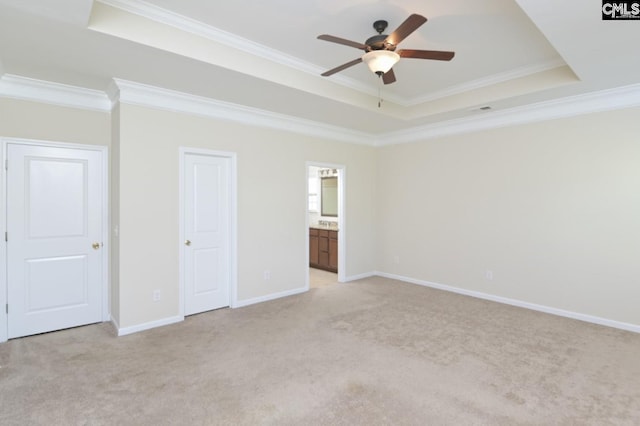 unfurnished bedroom with ornamental molding, connected bathroom, a raised ceiling, and light carpet