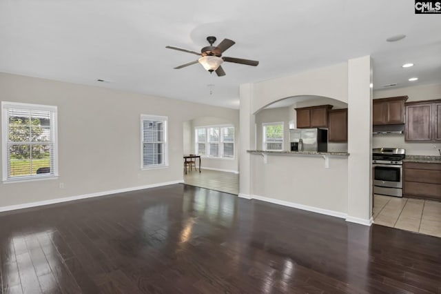 unfurnished living room featuring wood-type flooring, a healthy amount of sunlight, and ceiling fan