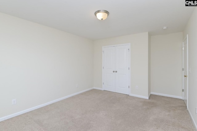 unfurnished bedroom with light colored carpet and a closet