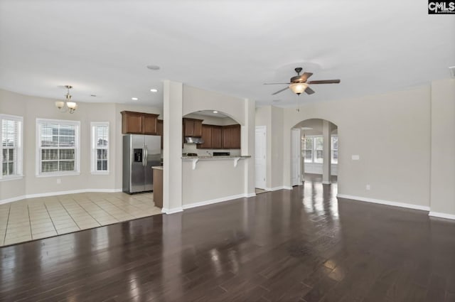 unfurnished living room featuring ceiling fan with notable chandelier and light hardwood / wood-style flooring