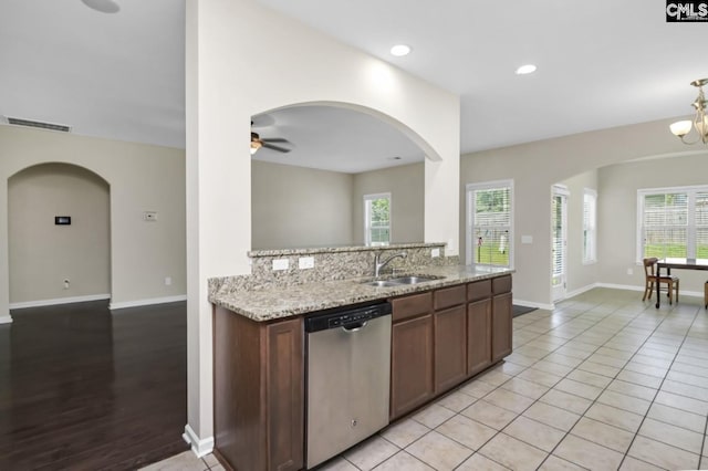 kitchen with ceiling fan with notable chandelier, dishwasher, sink, decorative backsplash, and light stone countertops