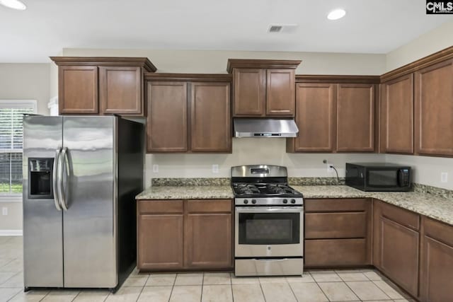 kitchen featuring light stone counters, light tile patterned floors, and stainless steel appliances