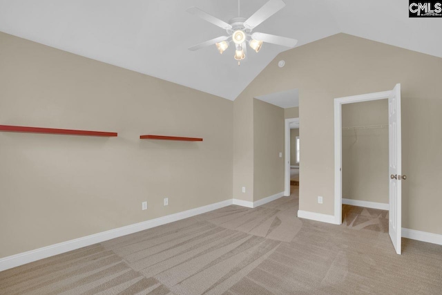 unfurnished bedroom featuring a closet, a spacious closet, vaulted ceiling, and light carpet