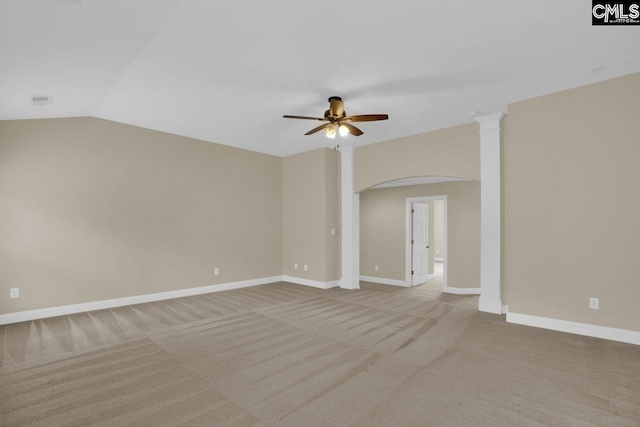 carpeted empty room with vaulted ceiling, ceiling fan, and decorative columns