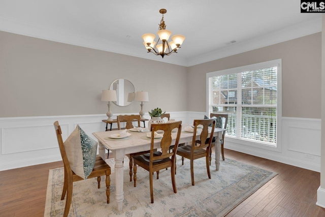 dining room featuring an inviting chandelier, ornamental molding, and dark hardwood / wood-style flooring