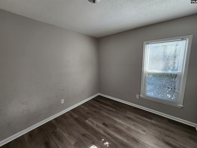 spare room featuring dark hardwood / wood-style floors and a textured ceiling