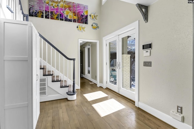 foyer entrance featuring hardwood / wood-style floors, french doors, and a high ceiling