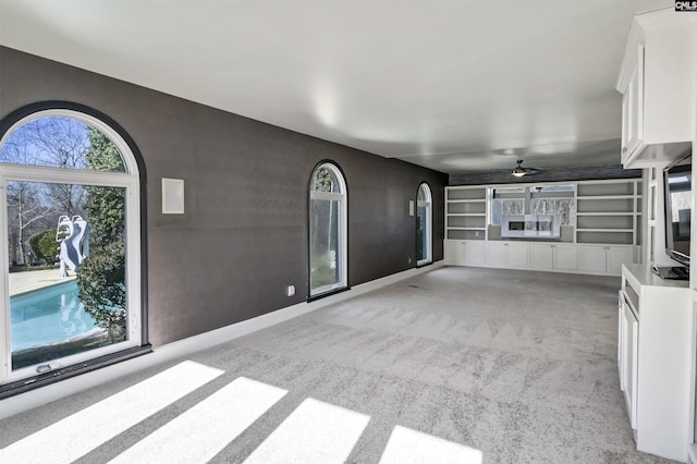 unfurnished living room with light colored carpet and ceiling fan